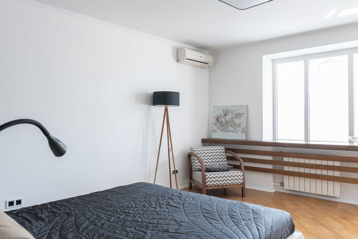 Best 120V DIY mini split: a 115V wall-mounted ductless mini split head in a bright bedroom above a standard household outlet
