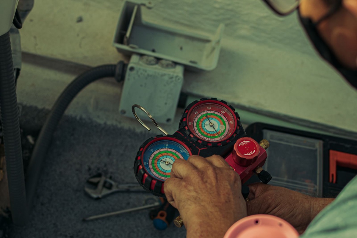 Pioneer mini split vacuum pump required: a technician reading refrigerant manifold gauges while evacuating a flare-type mini split line set