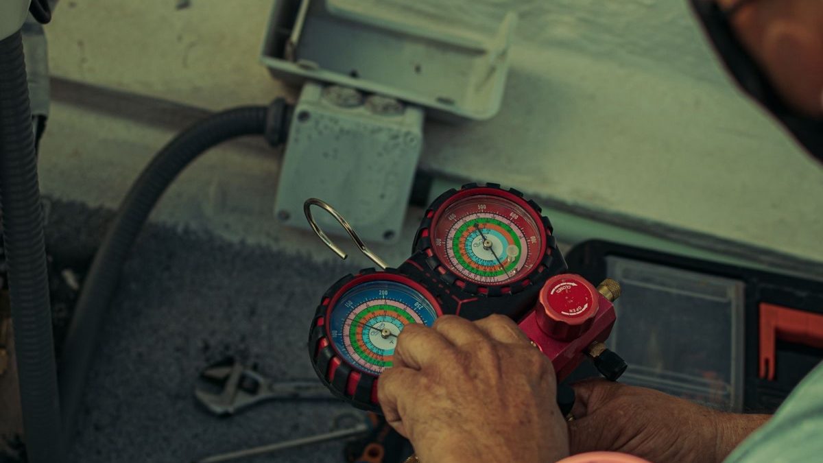 Technician holds manifold gauges near a mini split outdoor unit, comparing senville vs pioneer mini split installation tools nearby